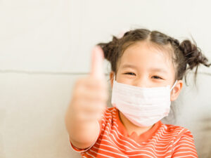 girl wearing face mask show thumbs up