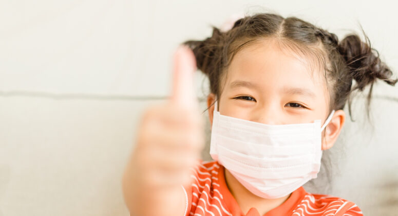 girl wearing face mask show thumbs up