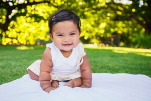 baby girl sitting unsupported and starting to take first crawling steps on her own