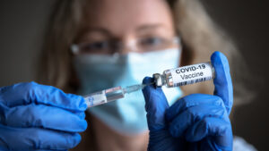 female doctor holds syringe and bottle with vaccine for coronavirus