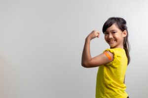 Girl with bandage on her arm smiling. 